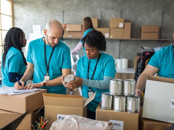 A group of volunteers in teal shirts taking donations for charity