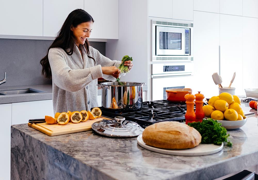 woman preparing food in her kitchen with a marble island