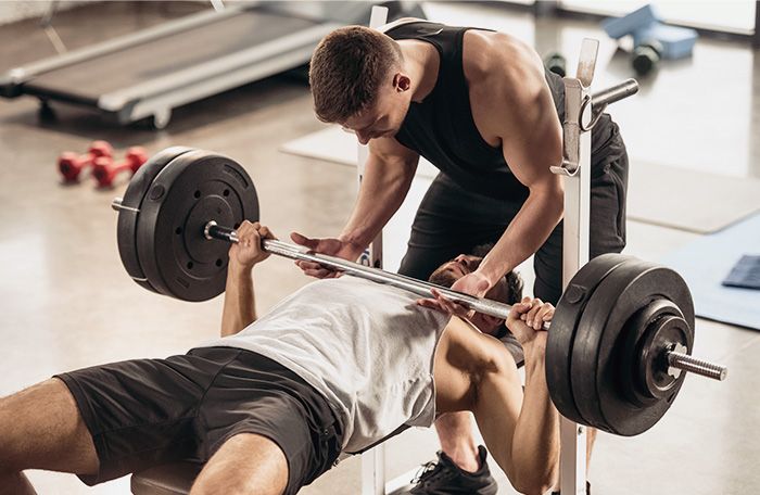 Personal trainer spotting a client during a benchpress