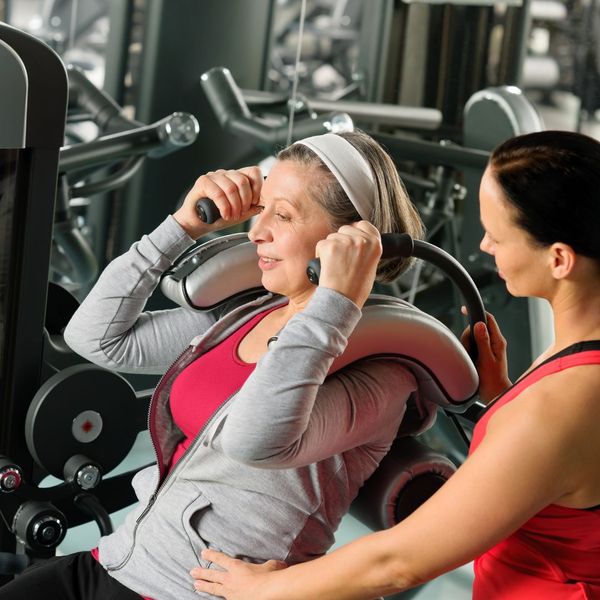 personal trainer coaching client on gym equipment