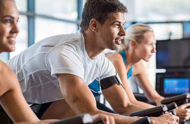 men and women cycling in a gym