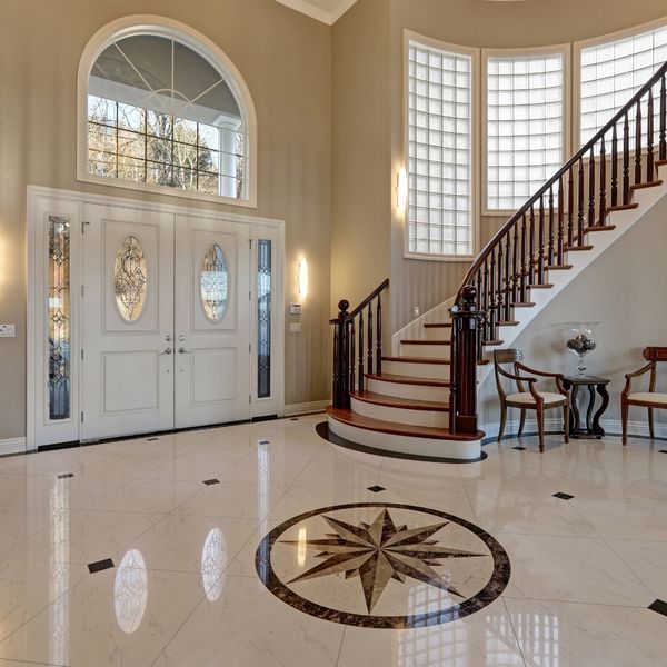 An elegant entryway with polished marble floor tiles and a central compass rose medallion. The grout is immaculate, contributing to the luxurious feel of the space. An elegant entryway with polished marble floor tiles and a central compass rose medallion. The grout is immaculate, contributing to the luxurious feel of the space.