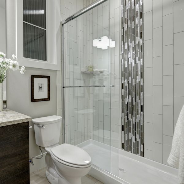 A modern bathroom featuring a walk-in shower with white subway tiles and a decorative mosaic accent strip. The grout is clean and bright, enhancing the room's sparkle. A modern bathroom featuring a walk-in shower with white subway tiles and a decorative mosaic accent strip. The grout is clean and bright, enhancing the room's sparkle.