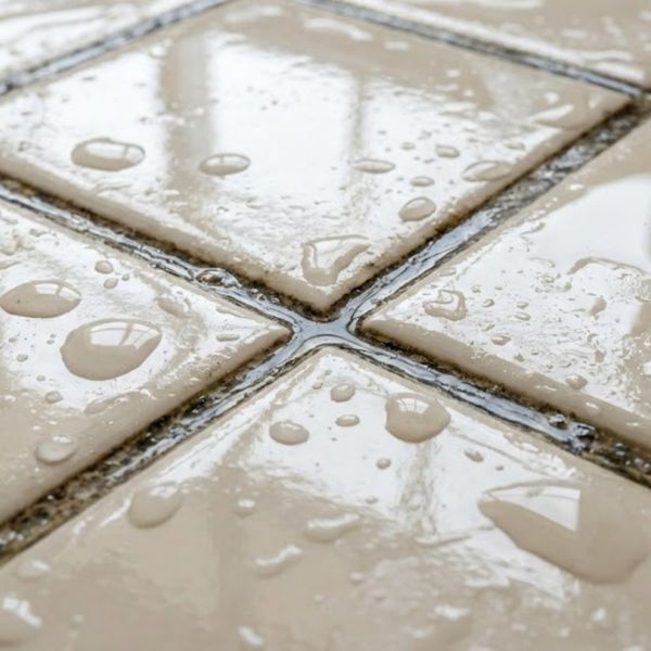 wet bathroom tiles covered in condensation with darkened, damp grout lines