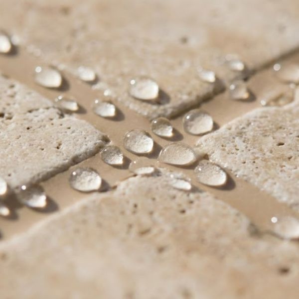 Water beads resting on the surface of freshly sealed grout