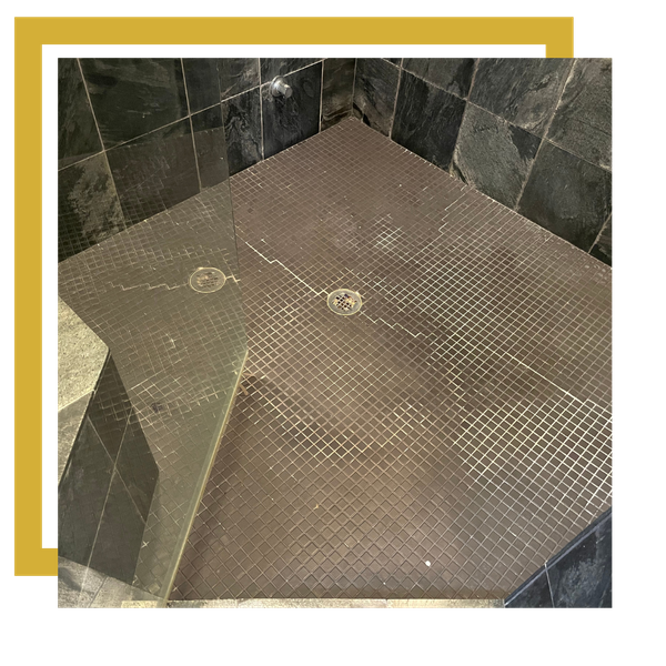 Mosaic tile shower floor with dark grout needing repair