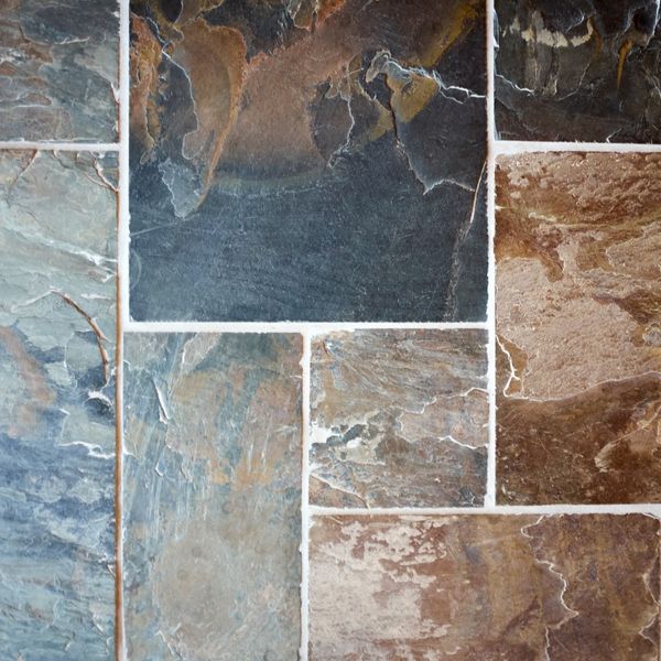 A close-up of natural slate tiles in various earthy tones, with clean, light-colored grout lines that highlight the texture and color of the stone. A close-up of natural slate tiles in various earthy tones, with clean, light-colored grout lines that highlight the texture and color of the stone.