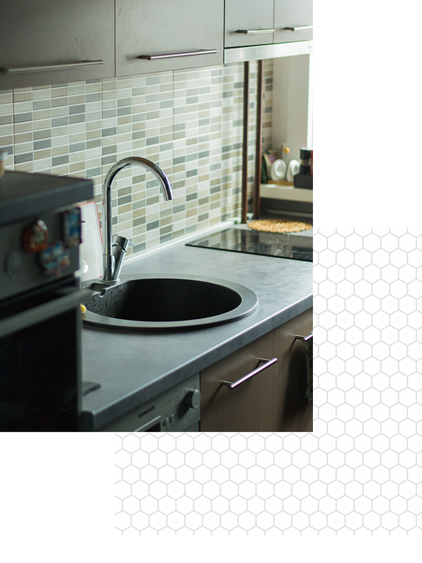 A round kitchen sink with green backsplash tiles