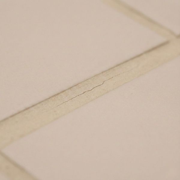 ubtle hairline crack running along a line of beige grout between floor tiles