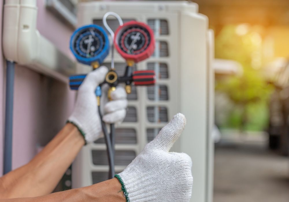 tech with thumbs up in front of HVAC system