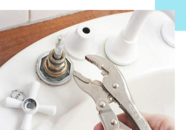 someone holding a wrench near a broken sink