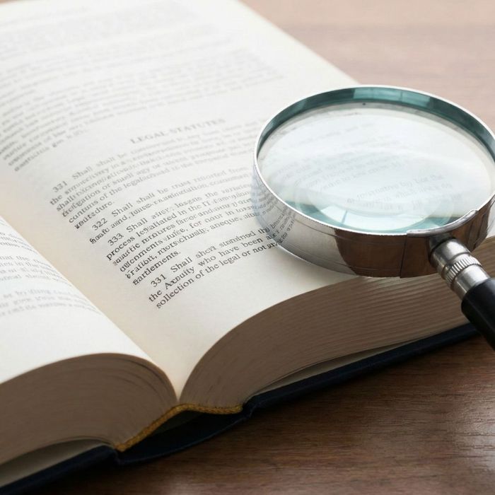 A law book open next to a magnifying glass representing legal research.