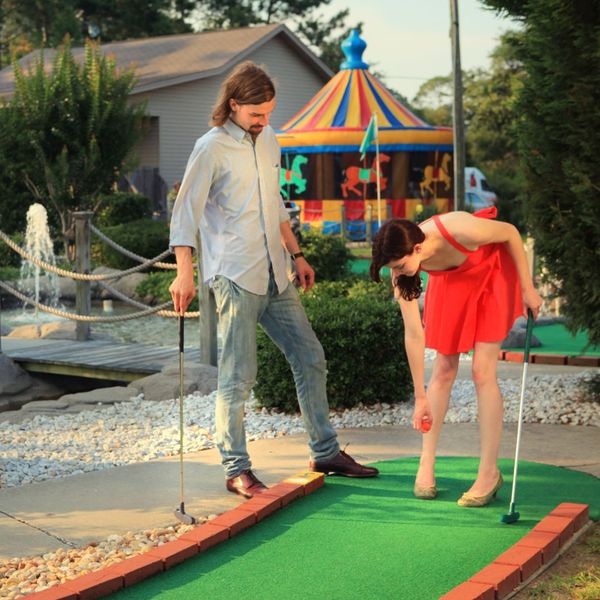 two people dressed up for a date playing mini golf