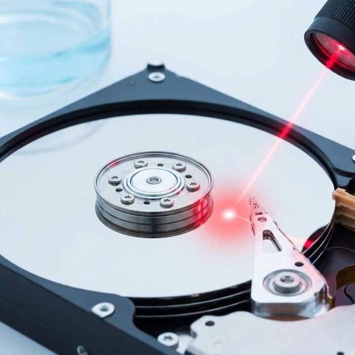 Macro photograph of a hard drive platter being scanned by a red laser for data recovery.