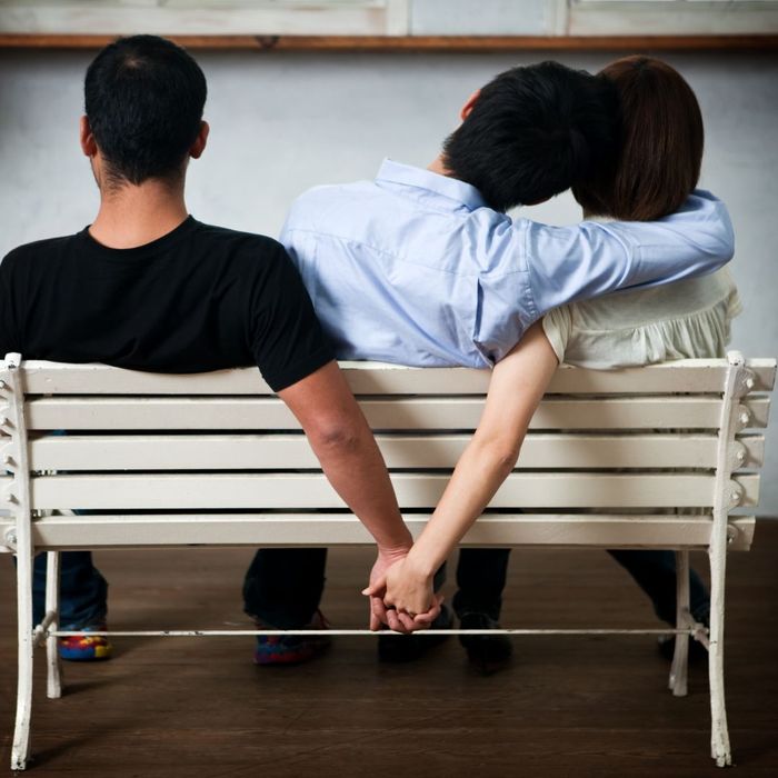 girlfriend holding hands with another man behind a bench