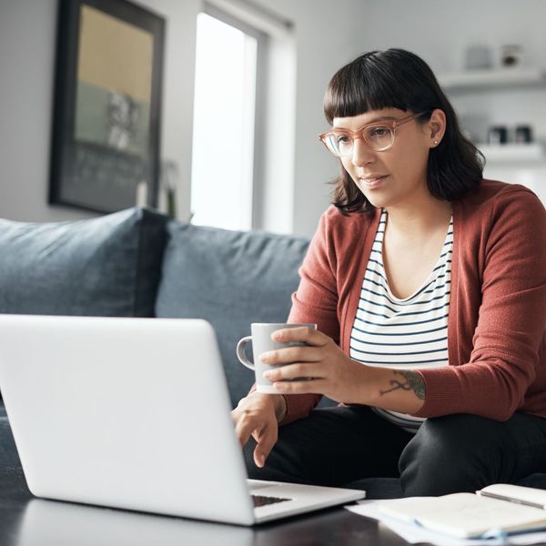 a woman working on a computer while holding a mug