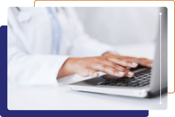 Close-up of a doctor's hands typing on a laptop keyboard.