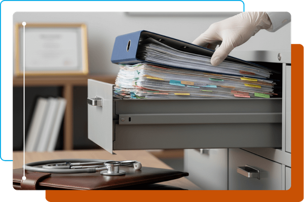 Gloved hand organizing medical files in a filing cabinet.