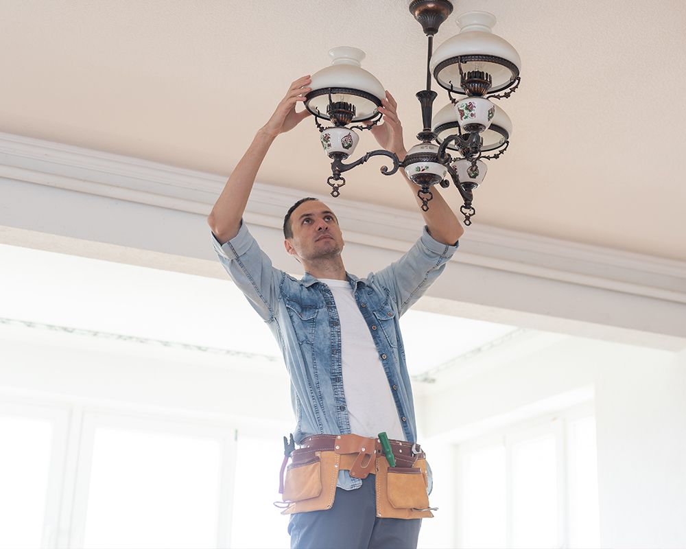 Electrical contractor installing chandelier in a home