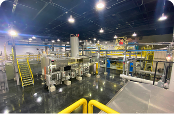 An overhead view of a complex light industrial processing plant, showing integrated machinery and electrical systems.