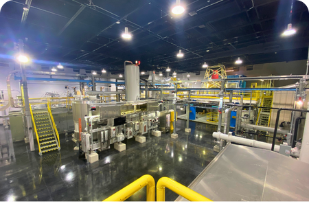 An overhead view of a complex light industrial processing plant, showing integrated machinery and electrical systems. An overhead view of a complex light industrial processing plant, showing integrated machinery and electrical systems.