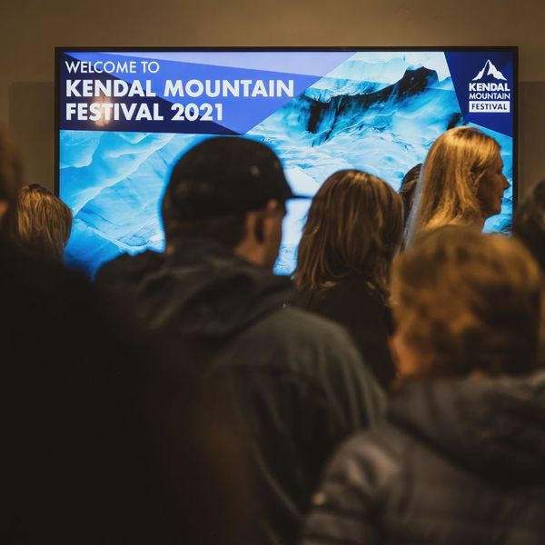 people standing in front of a tv displaying information