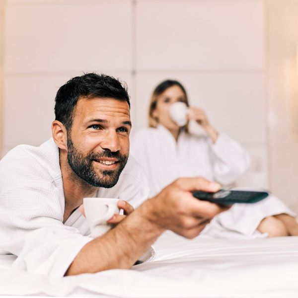 man pointing remote at TV in hotel