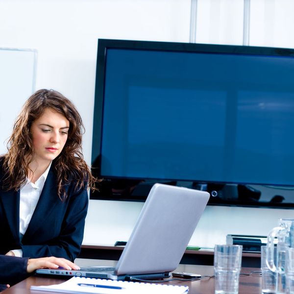 a business woman working on a computer in front of a large screen