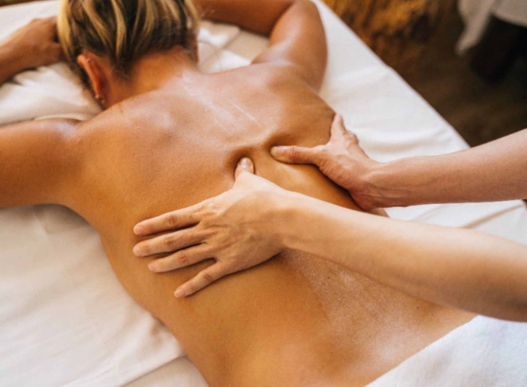 Image of woman receiving back massage, laying facedown on massage table Image of woman receiving back massage