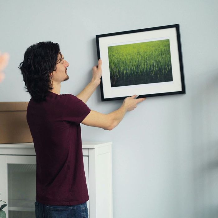 person hanging a picture on the wall