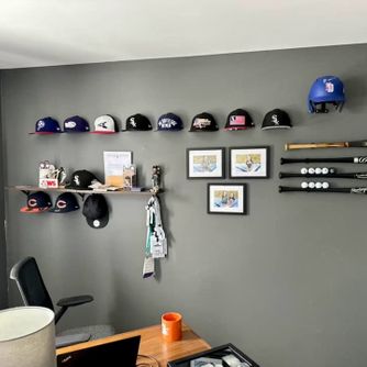 A real customer baseball cap collection displayed using The Original Squatchee™ adhesive hat hooks. Customer Hat Wall Display