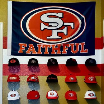 A real customer baseball cap collection displayed using The Original Squatchee™ adhesive hat hooks. Customer Hat Wall Display