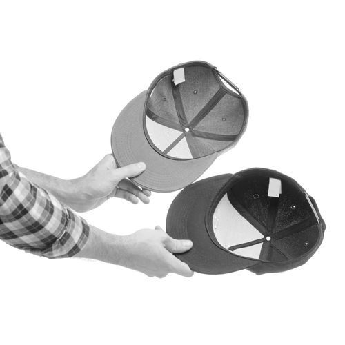 Hands holding a collection of baseball caps representing the start of a front-facing hat wall using The Original Squatchee™. Baseball Cap Collection Ready for Display