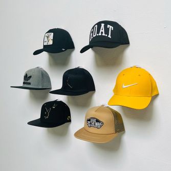 A large collection of baseball caps displayed front-facing on a wall using The Original Squatchee™ patented adhesive hat hooks. Baseball Cap Collector Hat Wall