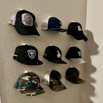 A real customer baseball cap collection displayed using The Original Squatchee™ adhesive hat hooks. Customer Hat Wall Display