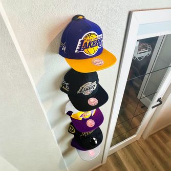 A real customer baseball cap collection displayed using The Original Squatchee™ adhesive hat hooks. Customer Hat Wall Display