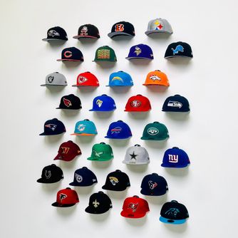 Sports baseball caps displayed front-facing in a man cave, basement, or entertainment room using The Original Squatchee™ adhesive hat hooks. Sports Hat Wall for Man Cave
