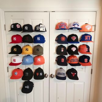 A real customer baseball cap collection displayed using The Original Squatchee™ adhesive hat hooks. Customer Hat Wall Display