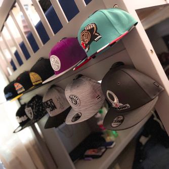 A real customer baseball cap collection displayed using The Original Squatchee™ adhesive hat hooks. Customer Hat Wall Display