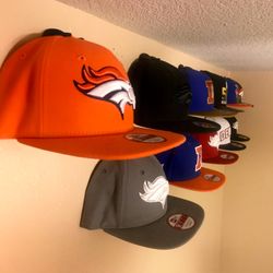 A real fan baseball cap collection displayed front-facing on a wall using The Original Squatchee™ adhesive hat hooks. Fan Hat Wall Display