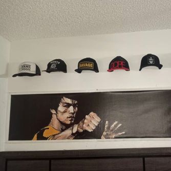 A real customer baseball cap collection displayed using The Original Squatchee™ adhesive hat hooks. Customer Hat Wall Display