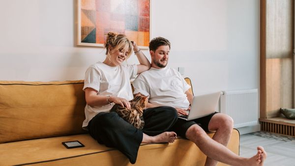 A young couple sharing an intimate and joyful moment on a sofa, representing trust and connection.