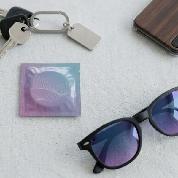 Flat lay of an Ampillar condom wrapper next to lifestyle accessories on a bright background.