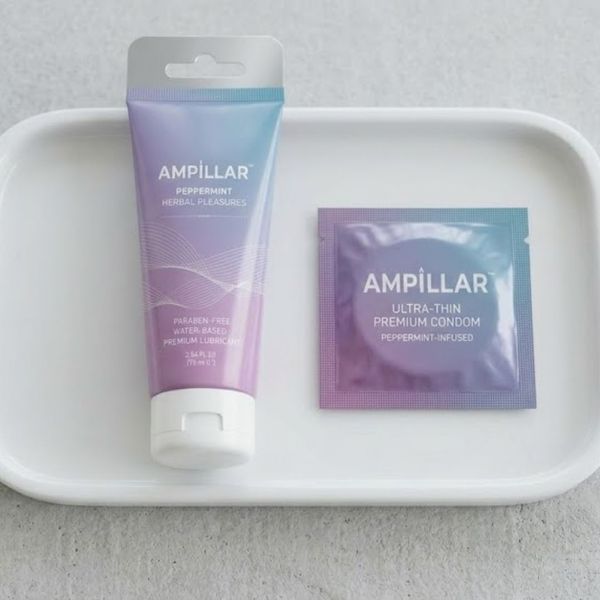 Ampillar lubricant and condom wrapper displayed on a clean white ceramic tray.
