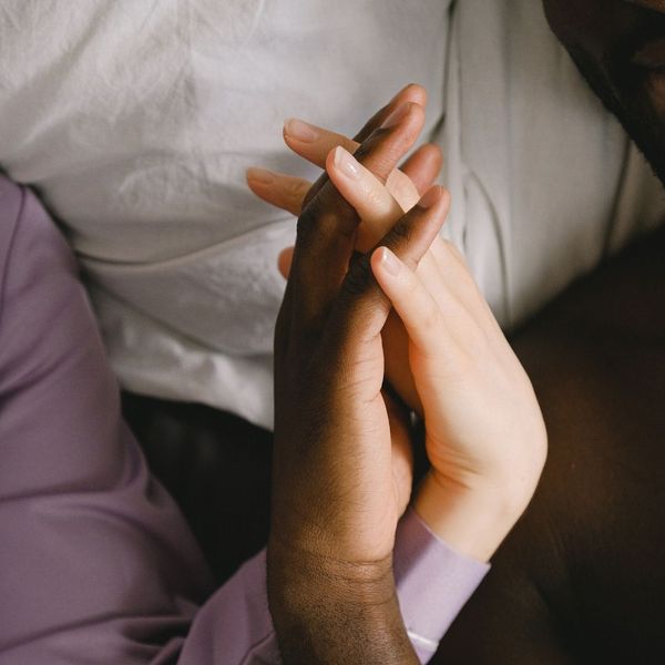 Two people’s hands intertwined in bed.