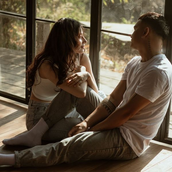 A couple talking while leaning against windows.