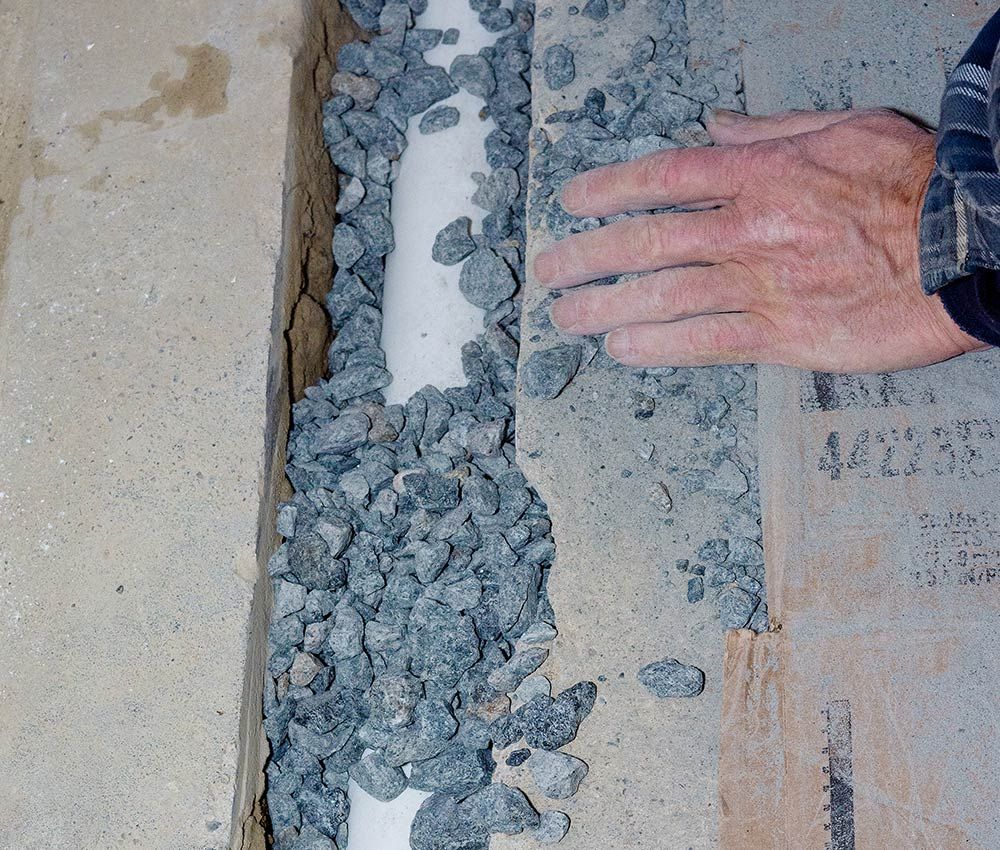 a person putting rock over a pipe in concrete