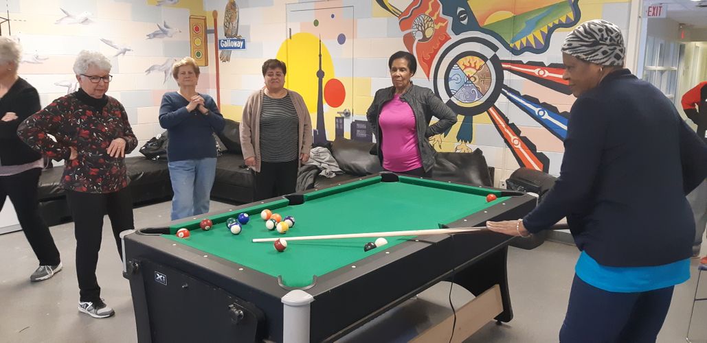 group of senior ladies play pool inside recreation room