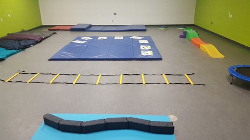 gym mats, trampoline, and children slide laid out inside safe gym area for small children