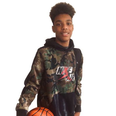 youth stands, smiling with basketball in hand 1.jpg